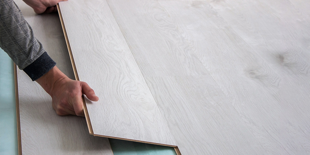 Instalación de piso laminado con herramientas sobre superficie de madera